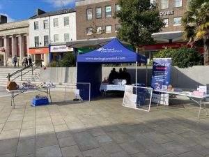 Photograph of an outdoor mental health awareness booth set up under a blue canopy labeled "Darlington Mind"